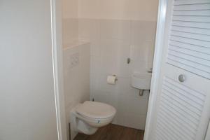 a white bathroom with a toilet and a sink at Heggerank 54 in Nieuwvliet +11 photos