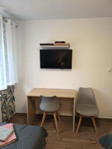 a desk with two chairs and a television on a wall at Apartament Japko in Gliwice