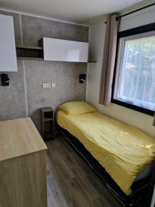a bedroom with a yellow bed and a window at Mobilehome familial in Gastes