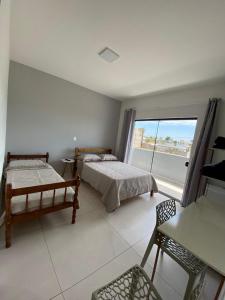 a bedroom with two beds and a large window at Pousada Barra Coast in Barra Velha