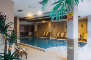 a large swimming pool in a hotel with chairs at Pirin Peaks Residence - next to Ski Lift in Bansko