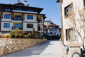 un edificio con un muro di pietra accanto a una strada di Pirin Peaks Residence - next to Ski Lift a Bansko