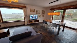a living room with a table and chairs and a tv at Fantastic home Beach Life 39A in De Koog