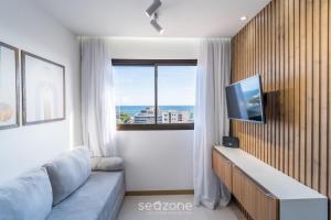a living room with a couch and a large window at Apartamentos em Prédio c/ Piscina na Ondina - SSA - HOA in Salvador