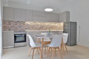 a kitchen with white cabinets and a table and chairs at Poli's Luxury suite @ N. Moudania in Nea Moudania