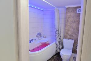 a bathroom with a pink tub and a toilet at Poli's Luxury suite @ N. Moudania in Nea Moudania +20 photos