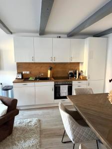 a kitchen with white cabinets and a wooden table at NORTH COAST Suites Hamburg-Duvenstedt nähe Golfclub 6 Gäste in Hamburg
