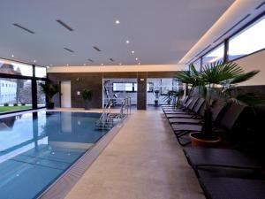 a pool in a building with chairs and plants at Hotel Rettenberg in Kolsass