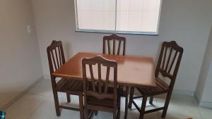 a dining room table with three chairs and a window at Central apartmento em Aperibé in Aperibé +25 photos