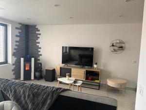 Una sala de estar con un sofá y un televisor. en Charmante petite maison, en Publier