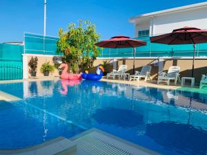 a swimming pool with two pink flamingos and umbrellas at Abuharee Grand in Hithadhoo