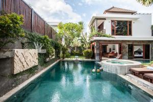 a swimming pool in front of a house at Villa Annecy in Seminyak