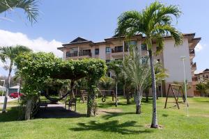a building with a park with palm trees and a swing at VG Sun Cumbuco Térreo WiFi Ar Cond 4 Pessoas in Paracumbuca