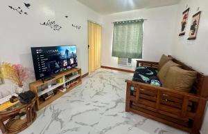 - un salon avec une télévision et un sol en marbre dans l'établissement HOMEY STAYCATION WITH PARKING near Diliman, Katipunan, Commonwealth, à Manille