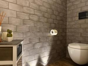 a bathroom with a toilet and a tiled wall at La Casupola by MONHOLIDAY in Monopoli