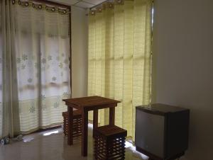 een kamer met een tafel, een tv en gordijnen bij Sungreen Safari Resort in Udawalawe