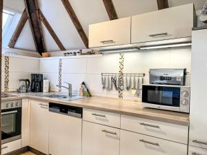 eine Küche mit weißen Schränken und einer Mikrowelle in der Unterkunft Holiday Home Knusperhaus Gretel by Interhome in Frankenau