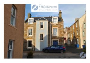a car parked in front of a house at The House on the Square- Coastal Townhouse in Saint Monance