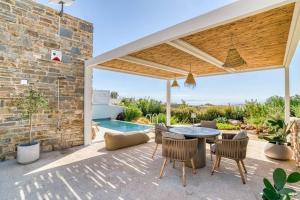 a patio with a table and chairs and a pool at Villa Gypsea - Paros in Aspro Chorio Paros