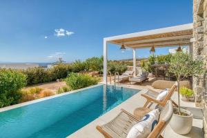 a swimming pool in a house with chairs and avisor at Villa Gypsea - Paros in Aspro Chorio Paros