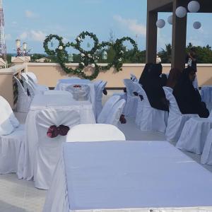 a group of three people sitting on white tables at Abuharee Grand in Hithadhoo +59 photos