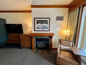 ein Wohnzimmer mit Kamin und Fernseher in der Unterkunft Ski In Ski Out Stowe Studio at Spruce Peak in Stowe