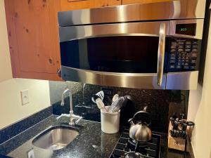 eine Küchentheke mit Spüle und Mikrowelle in der Unterkunft Ski In Ski Out Stowe Studio at Spruce Peak in Stowe + 13 Fotos