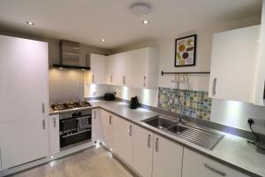 a kitchen with white cabinets and stainless steel appliances at High Wycombe Stunning Stylish Four Bedroom House in High Wycombe