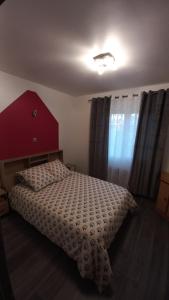 a bedroom with a bed with a red headboard and curtains at Hébergement chez Alice in Montauban +9 photos
