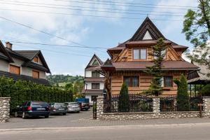 een groot houten huis met auto's voor het huis bij Willa Klimek Biały Dunajec in Zakopane