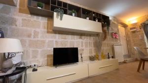 a living room with a tv on a stone wall at La Suite in Centro con vasca idromassaggio - Relax & Spa in Bari +12 photos