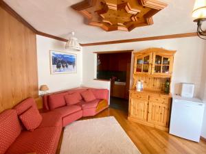 a living room with a red couch and a kitchen at SuperG apartment in St. Moritz