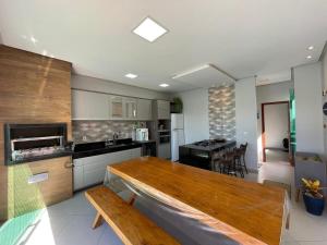 a large kitchen with a wooden table in it at Casa Rosa Pestana - min da Praia - PRADO BAHIA in Prado