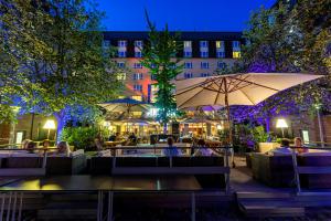 un patio con tavoli e ombrelloni di notte di Pentahotel Leipzig a Lipsia