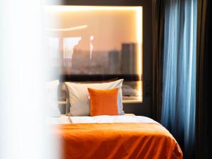 a bedroom with a bed with an orange blanket and pillows at JustStay Mülheim Hotel & Apartments in Mülheim an der Ruhr