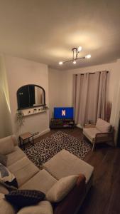 a living room with a couch and a tv at Cosy 3 Bedroom, 5 Bed House! in Headingley