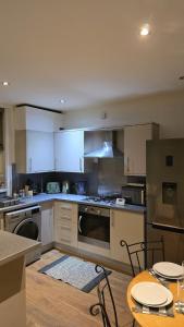 a kitchen with white cabinets and a table with chairs at Cosy 3 Bedroom, 5 Bed House! in Headingley +10 photos