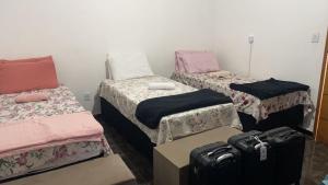 a room with three beds and luggage in it at Pousada América Aeroporto Viracopos Campinas in Viracopos