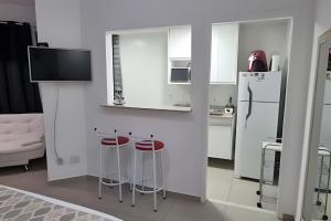 a white kitchen with stools and a refrigerator at Reserva do Sahy, Condado 2/305 in Mangaratiba