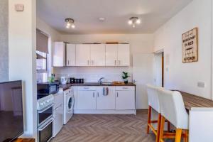 a kitchen with white cabinets and a table and a counter at Rayleigh Retreat-Spacious Family 3 Bed Apartment in Rayleigh +11 photos