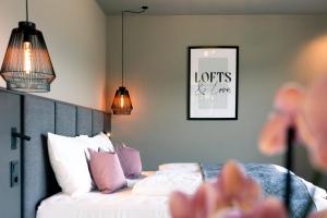 a bedroom with a bed with pink and white pillows at Belia Lofts - ADULTS ONLY - Apartments in Appiano sulla Strada del Vino