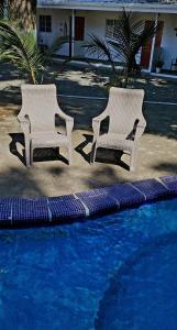 two white chairs sitting next to a swimming pool at ALOHA SUNZAL Piscina TV WIFI SURF playa sunzal in La Libertad