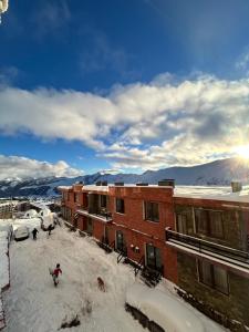 a person standing in the snow in front of buildings at Cozy and Tiny Nest in Gudauri in Gudauri