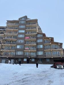un edificio en la nieve con gente caminando delante de él en Cozy and Tiny Nest in Gudauri, en Gudauri 2 fotos más