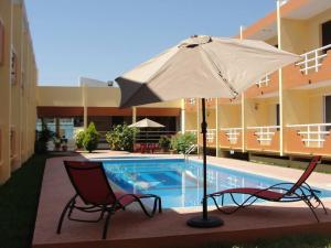 two chairs and an umbrella next to a swimming pool at Hotel La Media Luna Inn in Huejutla de Reyes