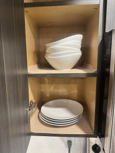 a cabinet with plates and a bowl in it at 1-Bedroom - On site Parking - near YQR Airport in Regina