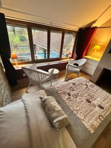 a bedroom with a bed and chairs and a large window at Le D'Tour Gourmand in Toulouse-le-Château +89 photos