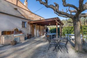 Un patio con una mesa y sillas debajo de un árbol. en Cal Contra, en Gélida