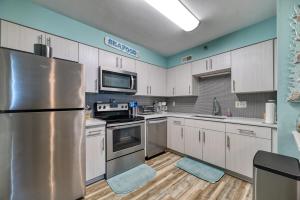 a kitchen with white cabinets and a stainless steel refrigerator at Oceanfront Condo Community with Pool in North Topsail Beach