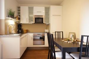a kitchen with white cabinets and a table with chairs at Stylish New City Appartement in Graz